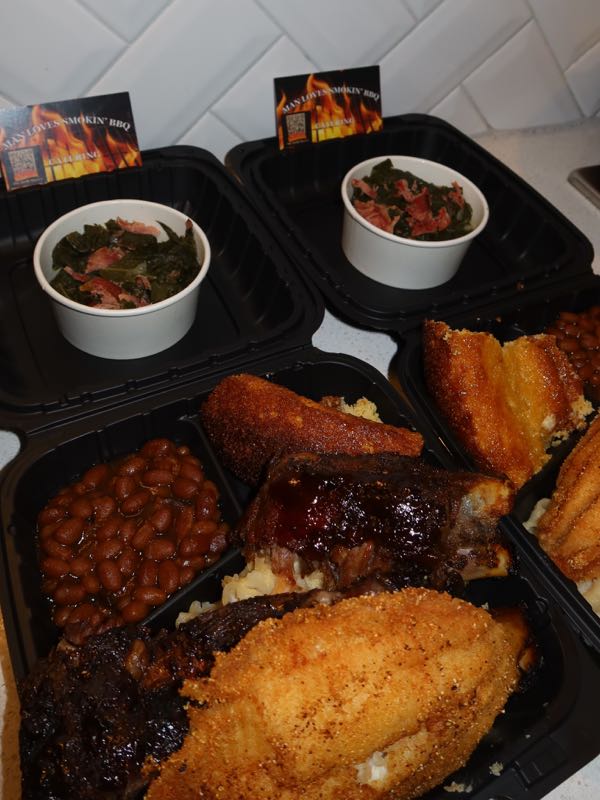 Two plates of sauced ribs, fried catfish, baked beans, and cornbread with collard greens